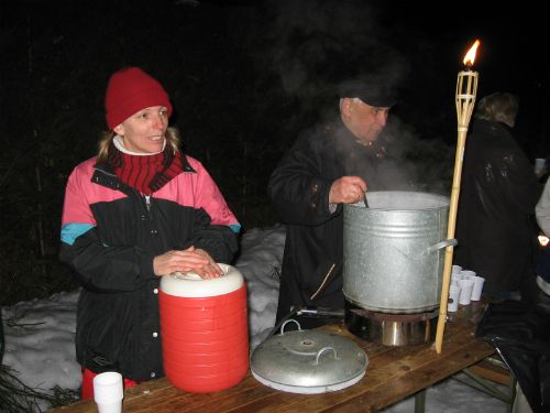 Delitev toplih napitkov ov večernem teku na smučeh ob baklah